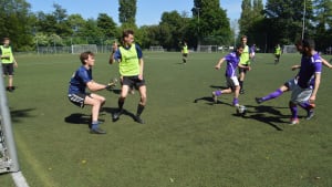 Facilitair medewerkers geven studenten voetballes op Roeterseilandtoernooi